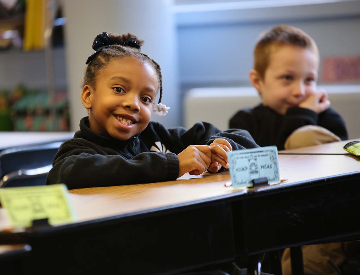 Elementary student smiling and posing together in a classroom.